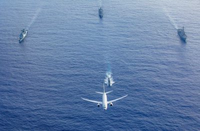 A U.S. Navy P-8 Poseidon flies above a formation of surface ships and submarines from the United States, Japan, and the Republic of Korea in the Philippine Sea during Pacific Vanguard 23, July 4, 2023. 