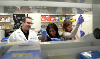 Tim Jarome watches as two students use pipettes to extract protein for a Western blot.