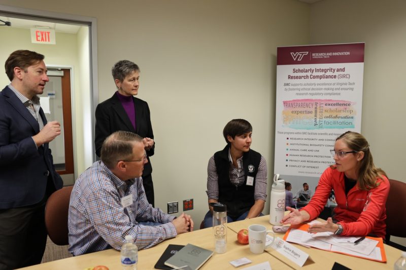 A group of research gathered around a table talking. 