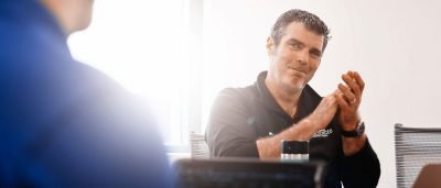 Ryan Pollyea claps his hands together while speaking with a colleague