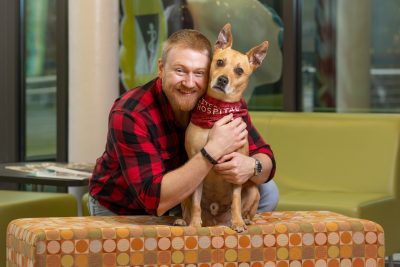 Rex Williams (at right) and his owner Ross Williams (at left) hugging and posing for a photo in the lobby of the Veterinary Teaching Hospital