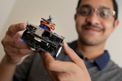 The CREATORS Virtual Institute will bring together cross-university undergraduate and graduate student teams to learn about cybersecurity challenges and technology through a year-long project experience. Sandeep Kumar Bijinemula, a computer engineering student, holds a small robot at the Hume Center in Arlington, Virginia. Photo by Ray Meese.