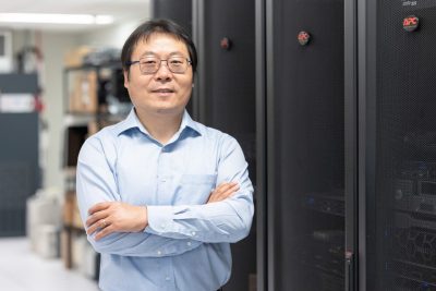 Guoqiang Yu stands in front of computing equipment at Virginia Tech Research Center