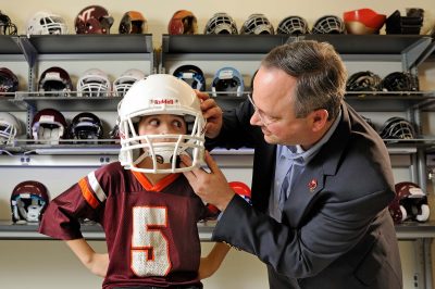 Researcher puts a football helmet on a child