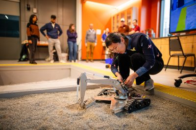 professor checks small excavotor digging in the rock pile