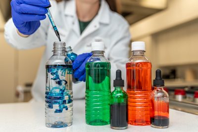 Scientist dropping food coloring into drink bottles