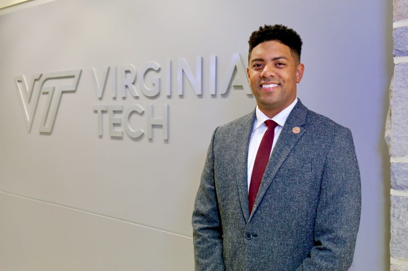 Kory Trott in front of a wall with the Virginia Tech logo.