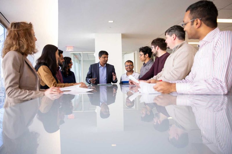 A meeting around a board room table with various people.