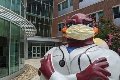 Medical school HokieBird with mask outside VTCSOM building.