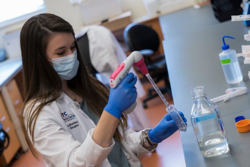 A researcher in a lab, wearing a mask.